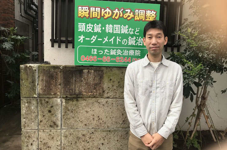 治療院の看板の前で立つ男性